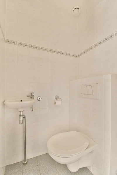 浴室里的一个白色厕所 后面有瓷砖地板和墙对墙的瓷砖 — 图库照片