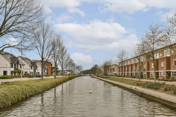 stock image a canal in the middle of a residential area with houses on both sides and trees lining the side of the river
