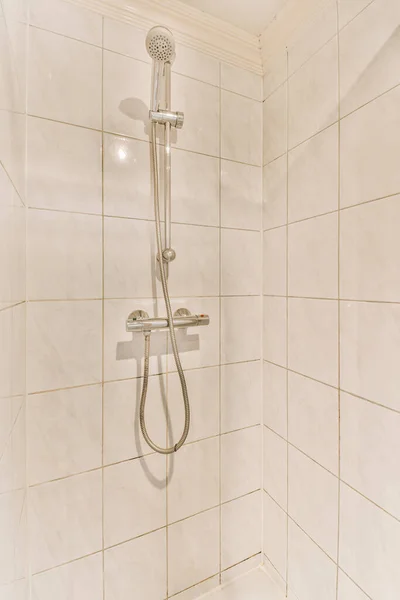 壁にシャワーヘッドと手すりのある白いタイル張りのバスルームは床にセラミックタイルで作られています — ストック写真