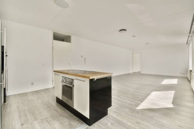 Beyaz duvarları, ahşap döşemeleri ve geniş pencereleri olan yeni bir apartmanda boş bir mutfak ve yemek alanı.