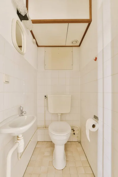 白いタイル張りの床と天井に木のトリムがある小さなバスルームは角にトイレがあります — ストック写真