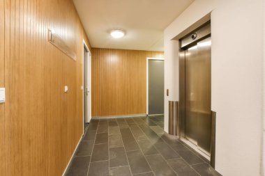 Her iki tarafında ahşap duvarlar ve döşemeler olan uzun bir koridor, merkezde bir asansöre çıkıyor.