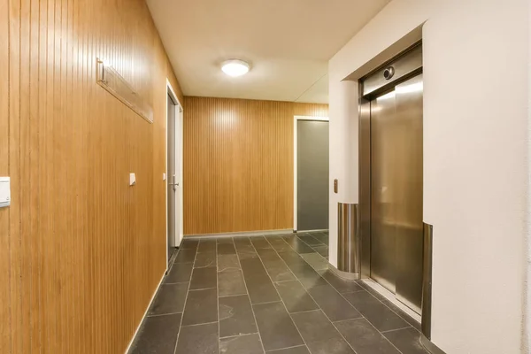 两边都有木制墙壁和瓷砖地板的长长的走廊 通往中间的电梯 — 图库照片