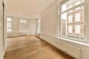 an empty room with wood flooring and large windows looking out onto the street in front of the apartment building