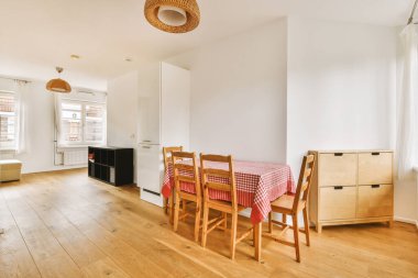 Beyaz duvarları, ahşap döşemeleri ve her iki tarafında ahşap döşemeleri olan bir odada yemek masası ve sandalyeler.