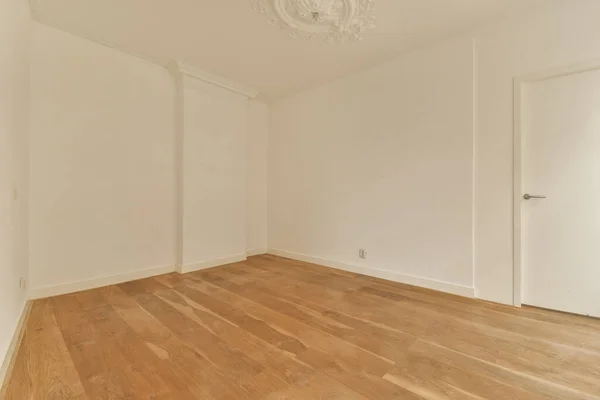 木製の床と白い壁のある空の部屋です角の壁に掛かるチャンネルを含みます — ストック写真