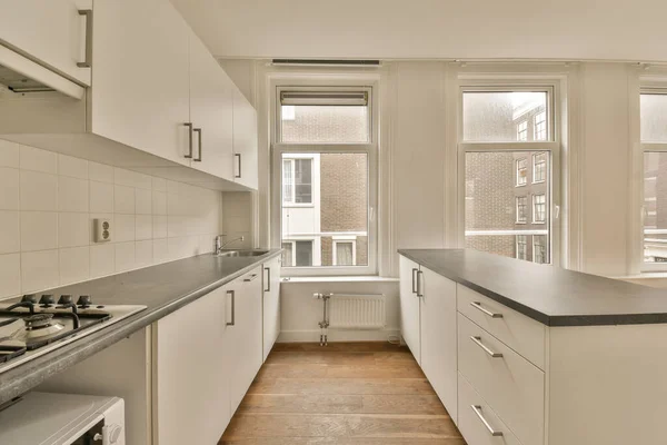 Eine Leere Küche Mit Weißen Schränken Und Schwarzen Arbeitsplatten Vor — Stockfoto