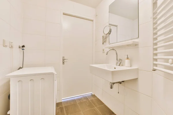シャワーエリアには白い壁と木の床があるバスルームがあります壁にはシンクと鏡があります — ストック写真