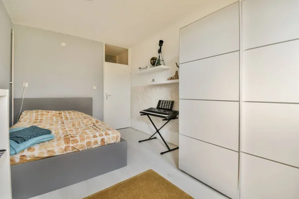 部屋の中央に白い食器棚とベッドがある寝室には小さな机があります — ストック写真
