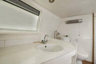 Köşesinde beyaz bir lavabo ve tuvalet olan bir banyo. İnsanların kullanması için bir duş odası olarak kullanılıyor.