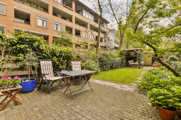 stock image an outdoor patio with chairs, tables and potted plants on the ground in front of a red brick building