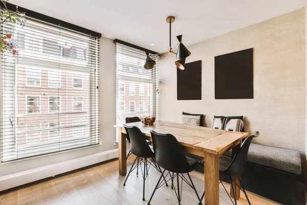 stock image a dining table and chairs in front of a window with shutters on the windowsilling is white brick