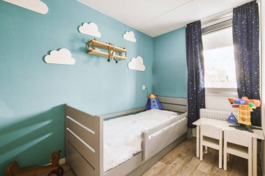 Mavi duvarları ve beyaz mobilyaları olan bir çocuk odası.