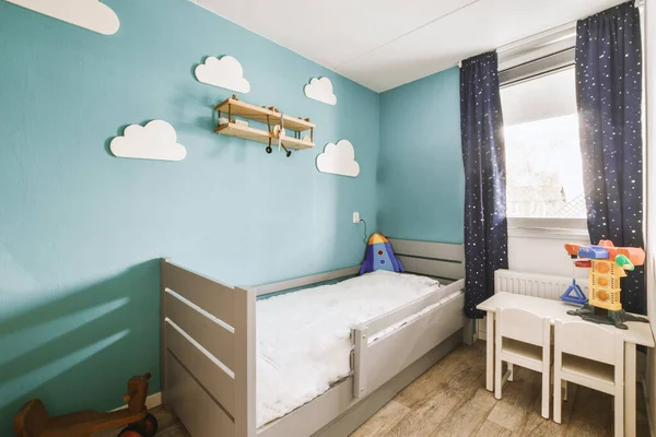 stock image a childs room with blue walls and white furniture, including a small cribe bed in the corner