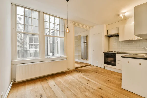 一间有木地板 白色墙壁和向街上望去的大窗户的房子里的一个空厨房和饭厅 — 图库照片