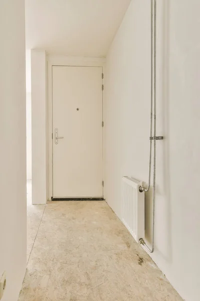 床と白い壁に誰もいない空の部屋 別の部屋につながる角にドアがあります — ストック写真