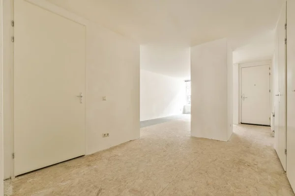 房间的中央是一个有白色墙壁和木地板的空房间 有一扇门通往另一个房间 — 图库照片