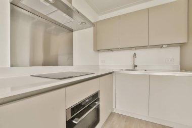 Resmin ortasında beyaz dolaplı bir mutfak ve fırın en üst kattan çekiliyor.