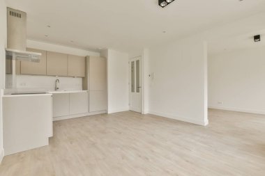 Odanın sağ tarafında ahşap döşemeli ve beyaz dolaplı boş bir oturma odası büyük bir mutfak alanıdır.