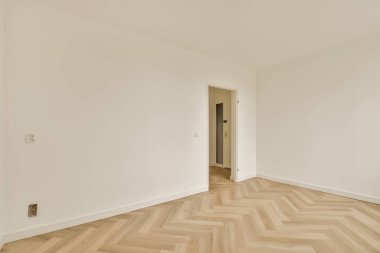 Odanın ortasında beyaz duvarları ve parke ahşap zemini olan boş bir oda çok temiz.