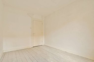 Beyaz duvarları ve ahşap zemini olan boş bir oda. Köşede başka bir odaya açılan bir kapı var.