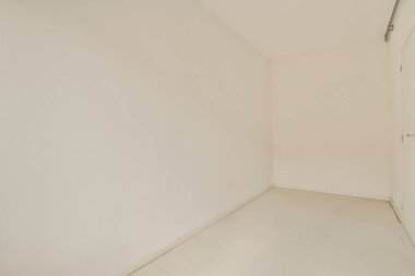 Beyaz duvarları olan boş bir oda. Köşede durup diğer duvara bakan kimse yok.