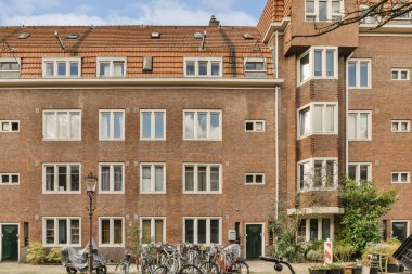 Güneşli bir günde sokakta yan yana park etmiş bisikletli bir apartman dairesi.