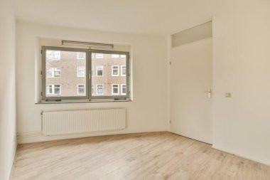 an empty room with wood floors and white walls, there is a large window in the wall to the right