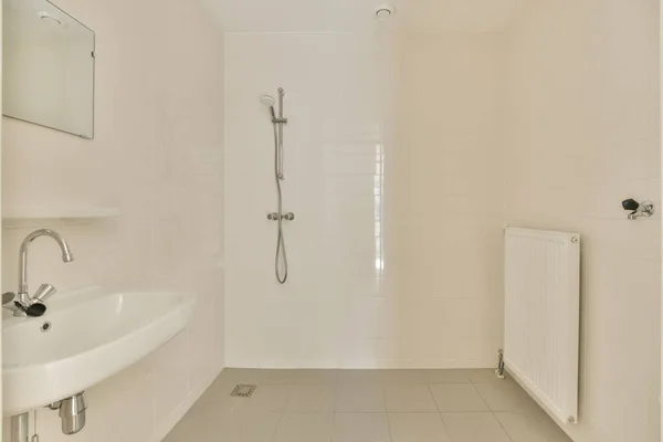 浴槽の角に白いタイル張りの床と壁にシャワーミキサーが設置されたバスルームがシンクの横にあります — ストック写真