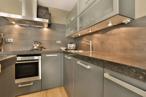 Eine Moderne Küche Mit Granitarbeitsplatten Und Edelstahlgeräten Der Wand Dahinter — Stockfoto