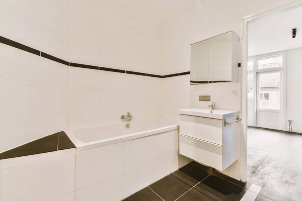 壁に黒と白のタイルのバスルームがある部屋のシンクミラーとトイレは空です — ストック写真