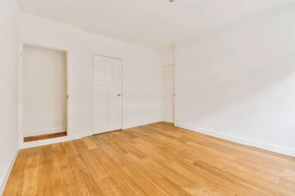 空荡荡的房间 一面是白色的墙壁 一面是木制的地板 另一面是一扇门 — 图库照片