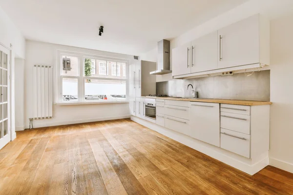 Una Cocina Con Suelos Madera Armarios Blancos Esquina Una Habitación — Foto de Stock