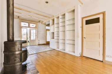 Odanın ortasında ahşap zemini ve açık şöminesi olan bir evin içinde, sağ tarafta.