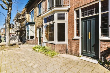 Kaldırımın kenarına bir bisiklet park edilmiş tuğla bir bina ve önünde bir ağaç - Swayr