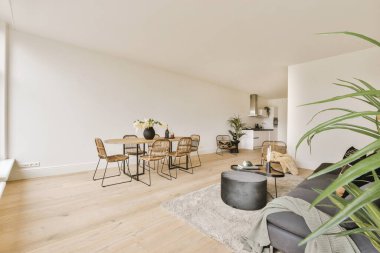 Odanın ortasında ahşap döşemeleri ve beyaz duvarları olan büyük bir bitki var.