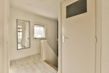 Odanın sol tarafında beyaz duvarları ve ahşap döşemeleri olan boş bir oda var.