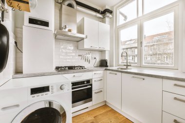 Çamaşır makinesi ve bulaşık makinesi olan bir mutfak tezgahı lavabonun önünde beyaz.