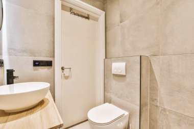 Lavabosu, tuvaleti ve aynası olan bir banyo kapının önündeki duş kabininin yanında.