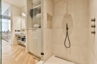 Duvarlarında ahşap döşeme ve bej kiremitler olan modern bir banyo ve duşta bir yürüyüş.