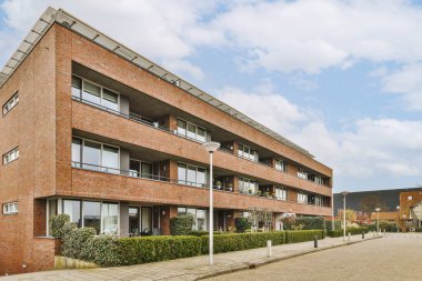 Önünde pencereleri ve balyaları olan tuğla bir bina boş bir park alanıdır.