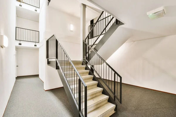 有的楼梯在空房间里 两边都有白色的墙壁和黑色的栏杆 有的楼梯通往 — 图库照片