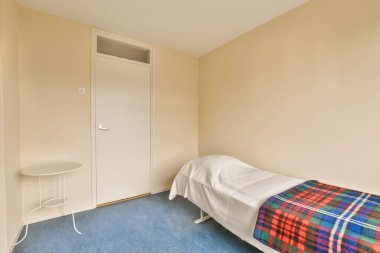 Sol köşesinde yatak, sandalye ve pencere olan küçük bir oda başka bir odaya açılan bir kapıdır.