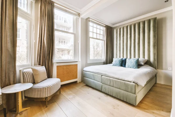 有一张床 椅子和窗户的卧室 墙上可以俯瞰城市的景观 — 图库照片