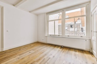 an empty room with wood flooring and white paint on the walls there is a window that looks out onto the street