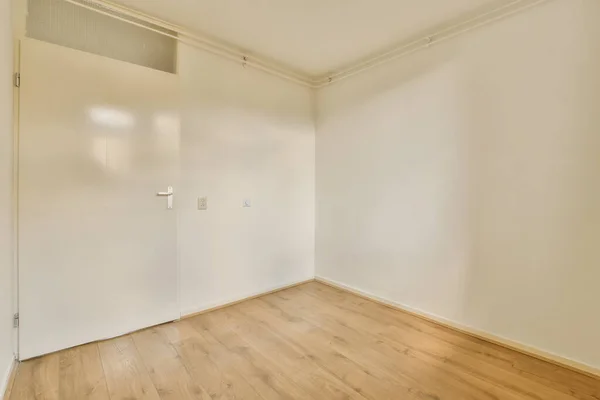 木製の床と白い壁のある空の部屋ドアは隅にクローゼットを明らかにするために開いています — ストック写真
