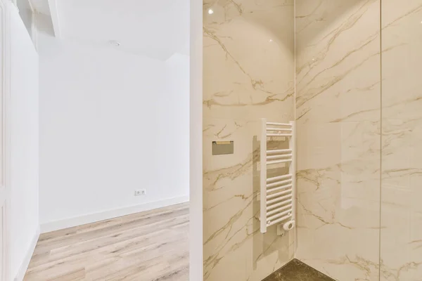 Stock image a modern bathroom with marble walls and floor to the right, there is a white towel rack on the wall