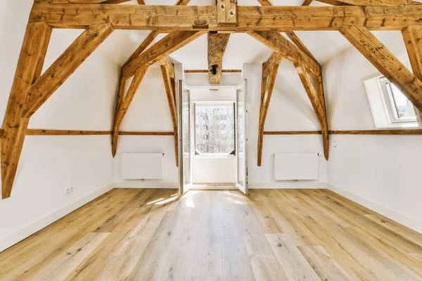 stock image an empty room with wood floors and wooden beams on the ceiling, looking towards the entrance to the living room