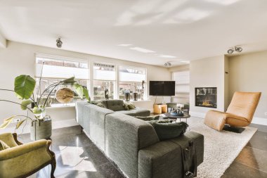 Odanın ortasında kanepeleri, sandalyeleri ve şöminesi olan bir oturma odası geniş pencereli.