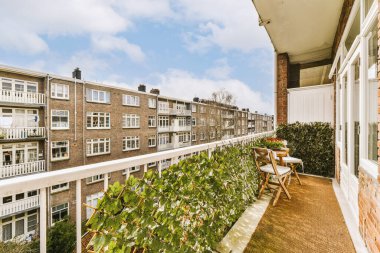 Apartman pencerelerinin önündeki korkuluklarda ve balknotlarda büyüyen bitkilerle dolu bir balkon.